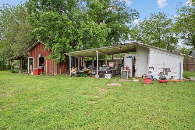 rear view of property with a yard, an outdoor structure, and a carport