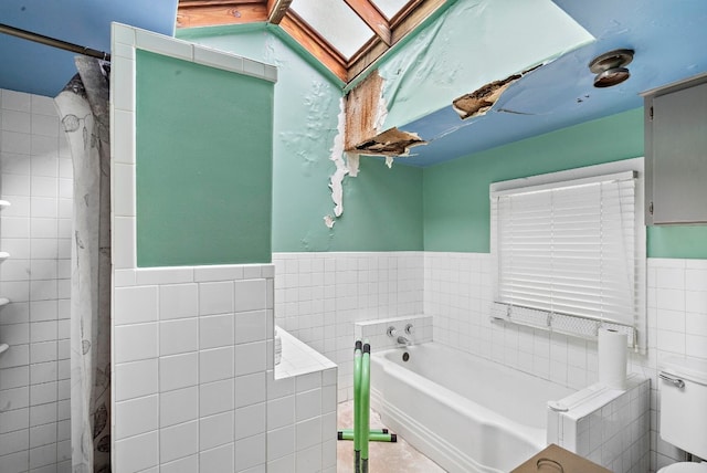 bathroom featuring a washtub, tile walls, and toilet