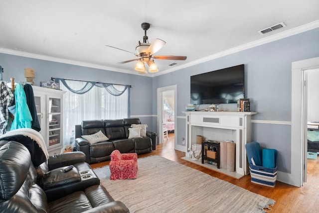 living room featuring wood-type flooring, ceiling fan, and ornamental molding