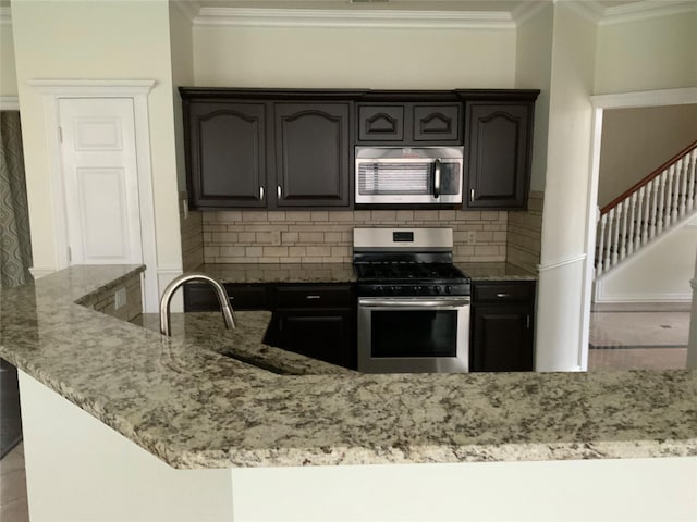 kitchen featuring light stone countertops, sink, stainless steel appliances, decorative backsplash, and ornamental molding