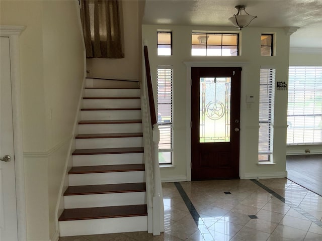 entrance foyer with crown molding and a textured ceiling