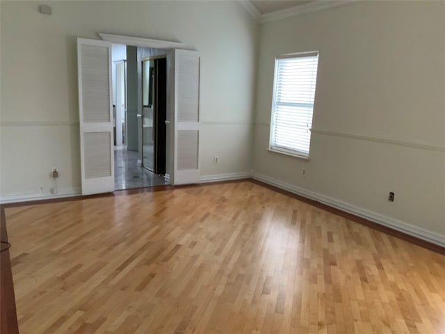 unfurnished room featuring light wood-type flooring and crown molding