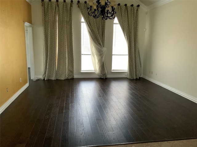 empty room with dark hardwood / wood-style floors, ornamental molding, and an inviting chandelier