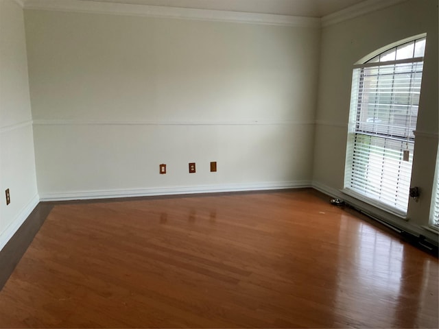 empty room with ornamental molding and dark wood-type flooring