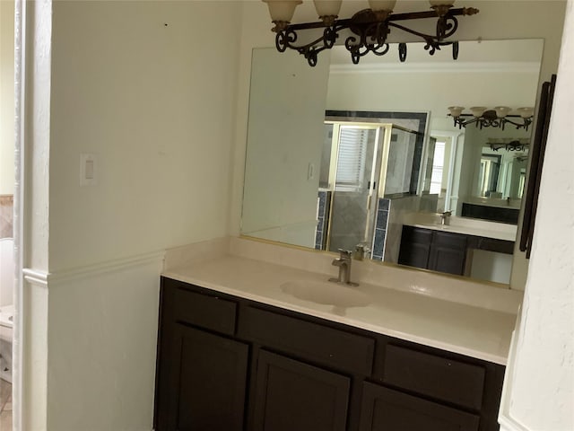 bathroom with toilet, a shower with door, vanity, and a notable chandelier