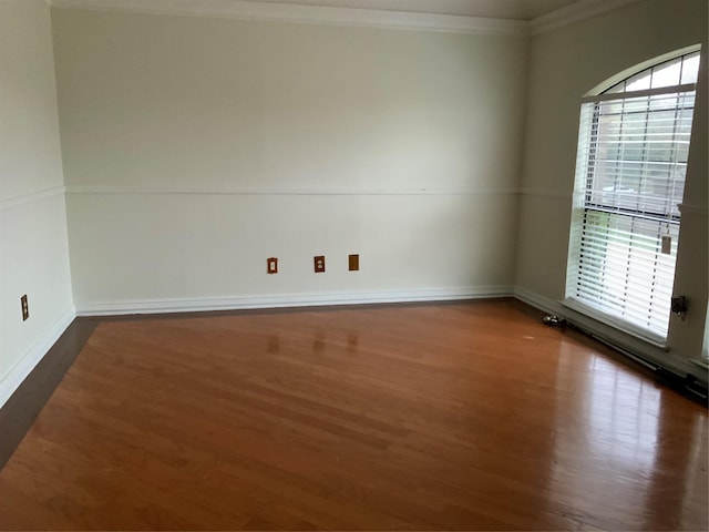 empty room with dark hardwood / wood-style floors, ornamental molding, and a wealth of natural light