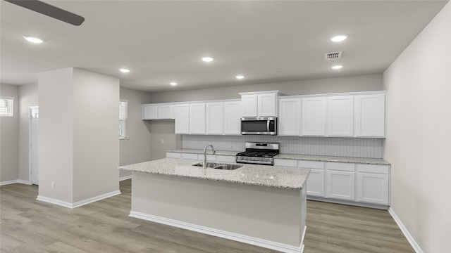 kitchen with backsplash, sink, light wood-type flooring, appliances with stainless steel finishes, and white cabinets