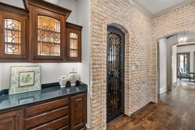 bar with dark hardwood / wood-style flooring and brick wall