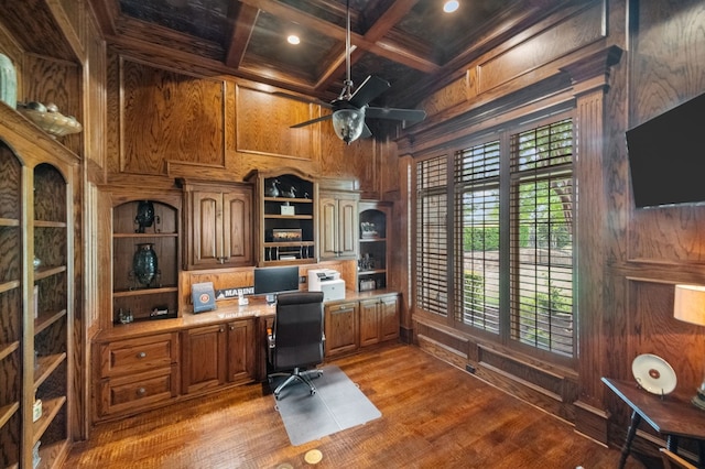 office area featuring wood walls, coffered ceiling, ceiling fan, built in desk, and beamed ceiling