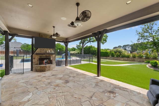 view of patio with an outdoor stone fireplace, a pool, and ceiling fan