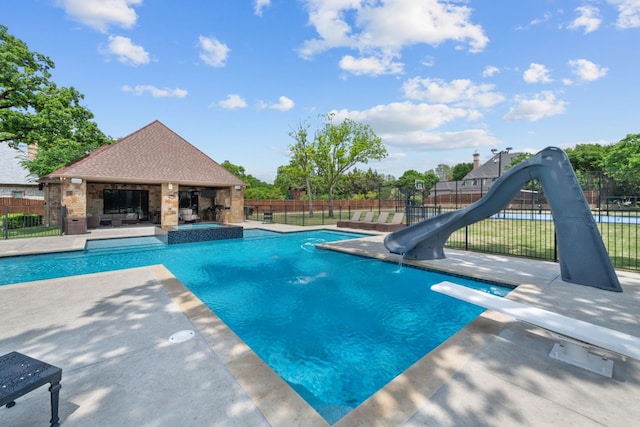 view of swimming pool featuring a diving board, a patio area, an outdoor fireplace, and a water slide