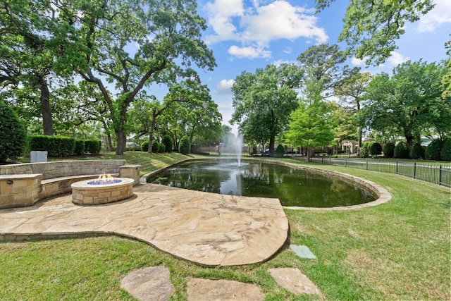 view of property's community with a water view and a lawn