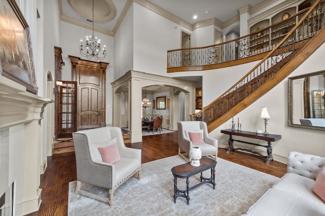 living room with hardwood / wood-style floors, a towering ceiling, an inviting chandelier, and crown molding