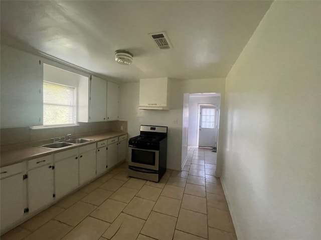 kitchen with sink, white cabinetry, light tile floors, and stainless steel gas range oven