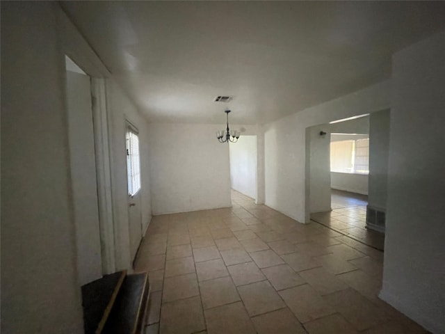 tiled spare room with a healthy amount of sunlight and an inviting chandelier