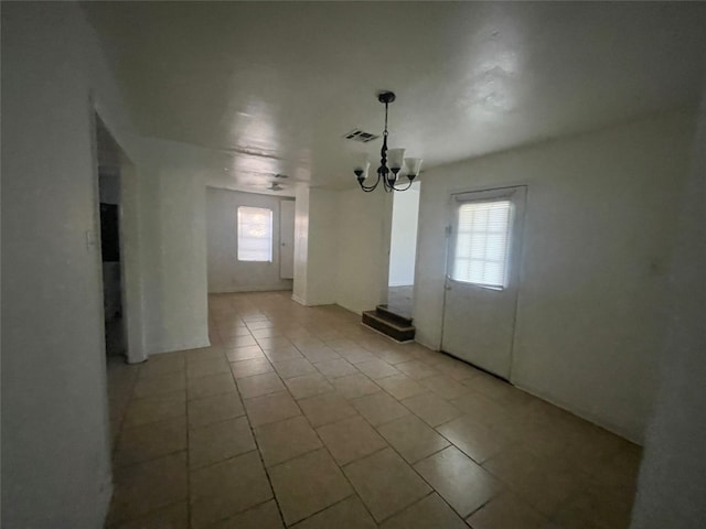 tiled spare room with an inviting chandelier