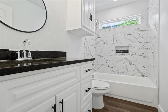 full bathroom featuring vanity, tiled shower / bath combo, toilet, and hardwood / wood-style floors