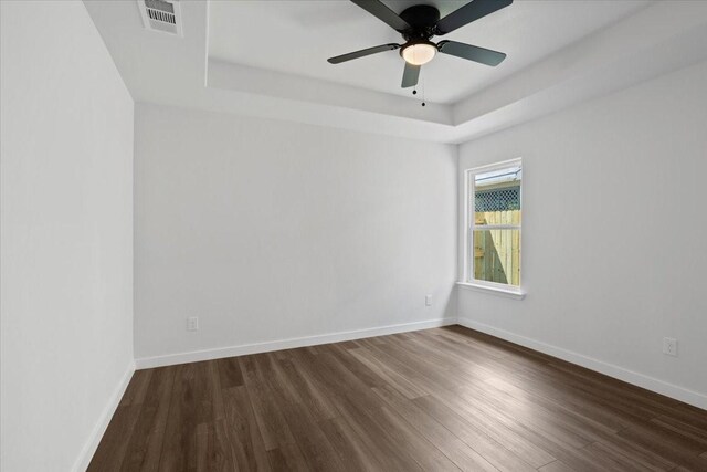 spare room featuring wood-type flooring, a raised ceiling, and ceiling fan