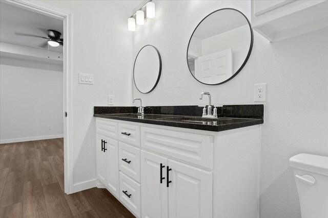 bathroom featuring dual vanity, toilet, ceiling fan, and hardwood / wood-style floors