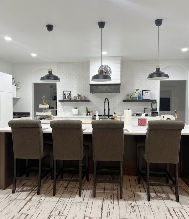 kitchen with a breakfast bar, sink, pendant lighting, and decorative backsplash