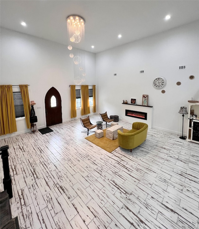 living room featuring an inviting chandelier, light hardwood / wood-style floors, and a high ceiling