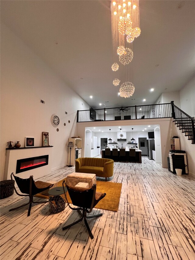 interior space with a towering ceiling, a notable chandelier, and light hardwood / wood-style flooring