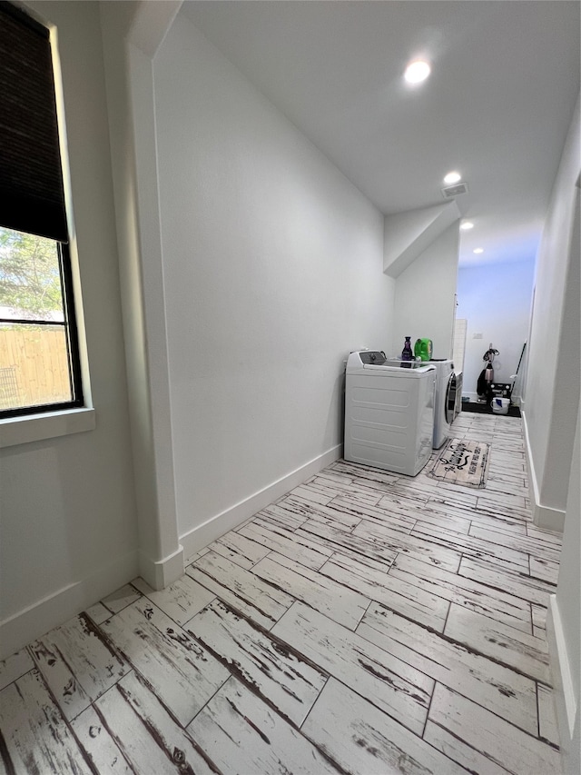 hallway with independent washer and dryer and light wood-type flooring