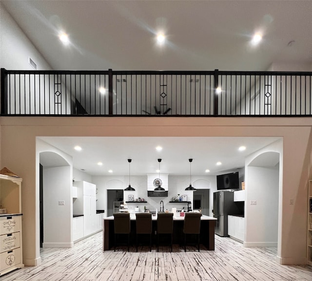 kitchen featuring stainless steel fridge, a large island with sink, and light hardwood / wood-style floors