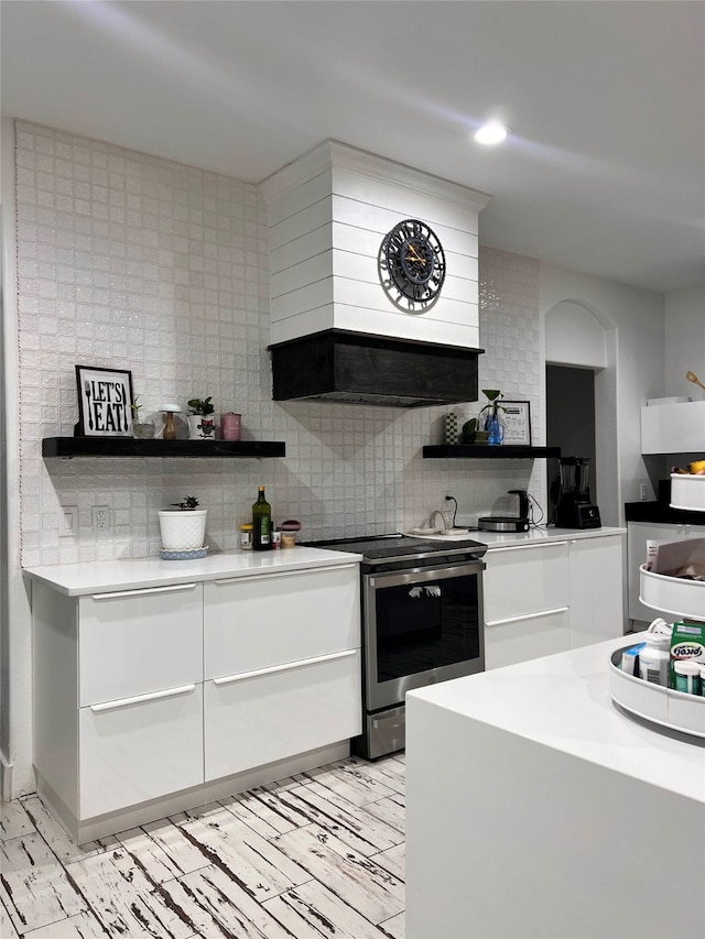 kitchen with white cabinets, decorative backsplash, premium range hood, and stainless steel electric range oven