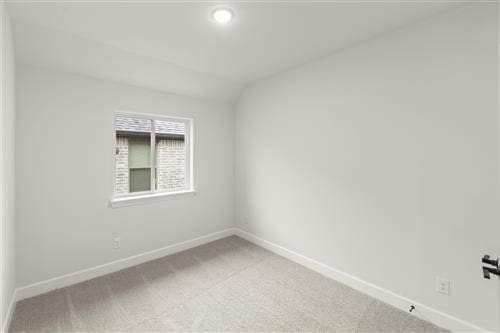 carpeted spare room featuring lofted ceiling