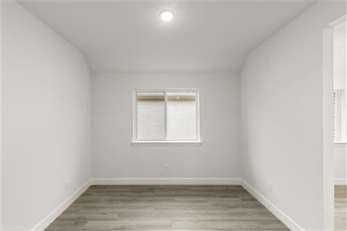 empty room featuring hardwood / wood-style flooring and vaulted ceiling