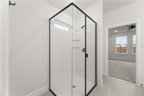 bathroom featuring tile patterned flooring, a shower with door, and ceiling fan