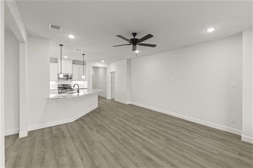 unfurnished living room with ceiling fan and dark hardwood / wood-style flooring