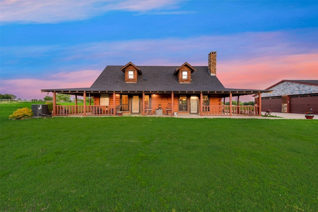 back house at dusk featuring a yard, a garage, and central air condition unit