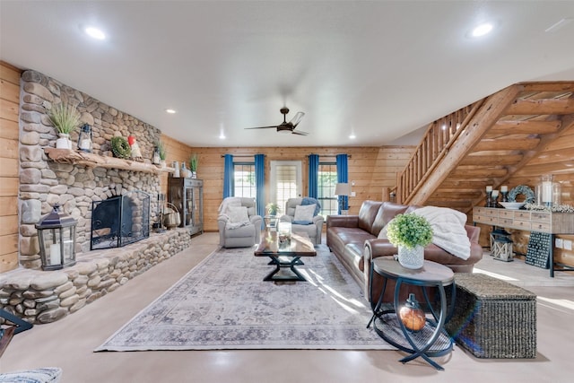 living room with ceiling fan, a fireplace, and wood walls