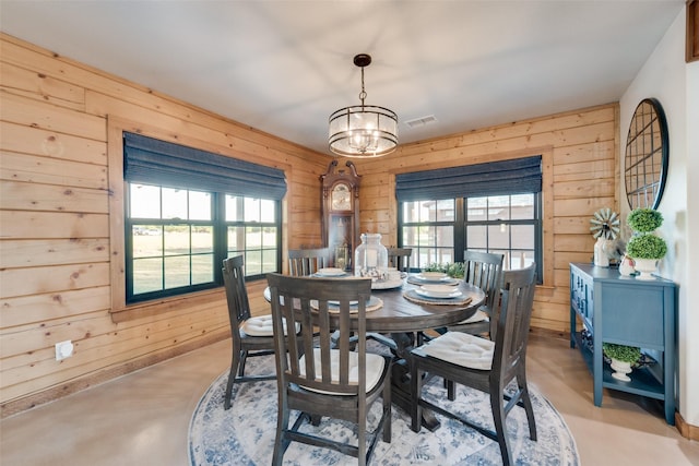 dining area featuring wooden walls and a chandelier