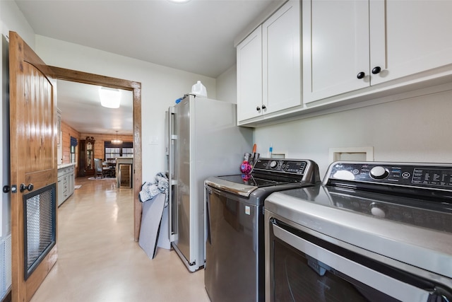 laundry room with separate washer and dryer and cabinets