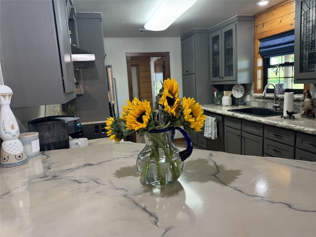 kitchen featuring light stone counters, dishwasher, sink, and gray cabinetry