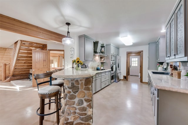 kitchen with a breakfast bar, sink, gray cabinetry, hanging light fixtures, and kitchen peninsula