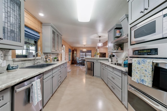 kitchen featuring wine cooler, sink, gray cabinetry, decorative light fixtures, and stainless steel appliances