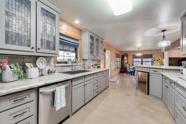 kitchen featuring sink, hanging light fixtures, gray cabinets, dishwasher, and beverage cooler