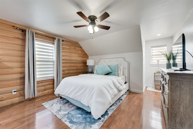 bedroom featuring ceiling fan, lofted ceiling, rustic walls, and multiple windows