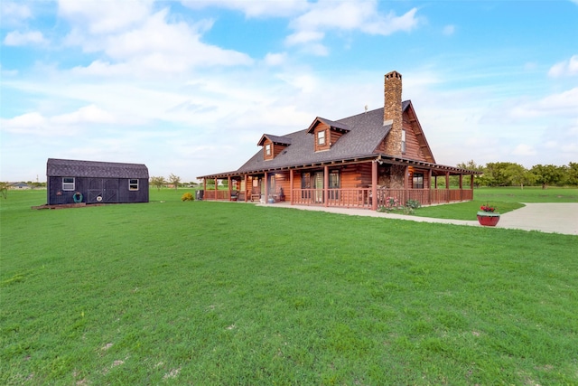 rear view of house featuring a yard, an outbuilding, and covered porch