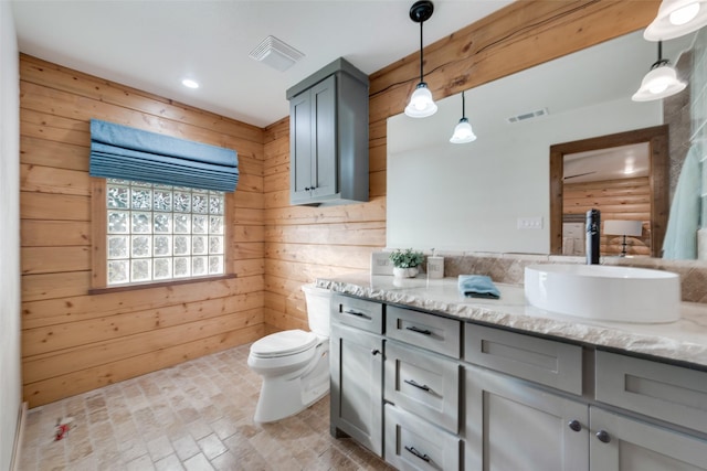 bathroom featuring vanity, toilet, and wood walls