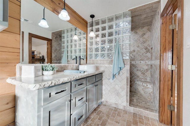 bathroom with tile walls, vanity, and a tile shower