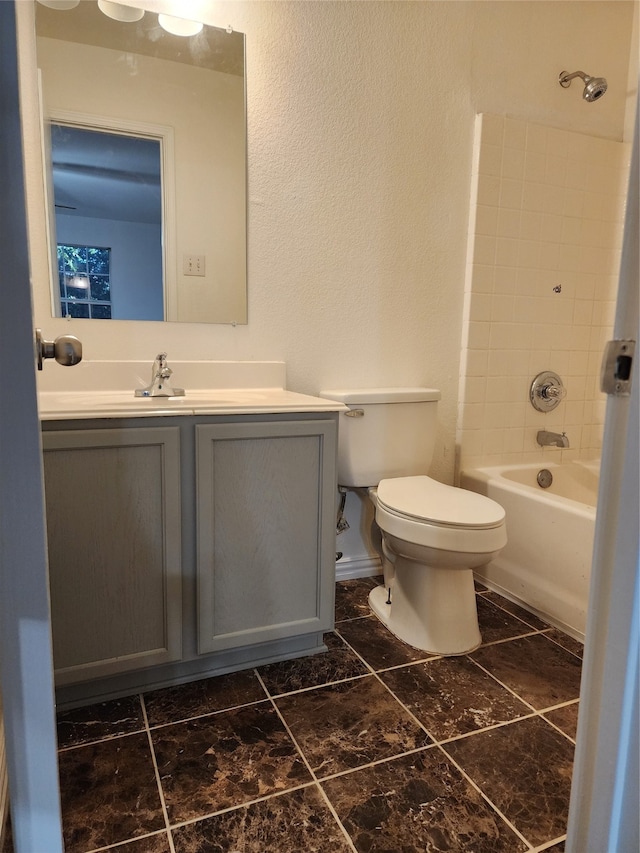 full bathroom with tile floors, tiled shower / bath, toilet, and vanity