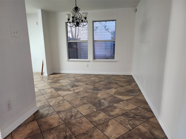 empty room with dark tile floors and an inviting chandelier