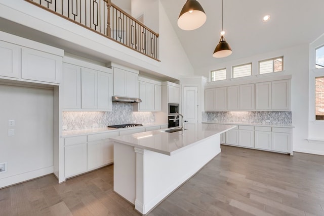 kitchen with pendant lighting, white cabinetry, sink, and high vaulted ceiling