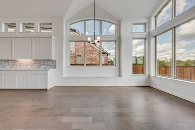 unfurnished sunroom featuring a healthy amount of sunlight, lofted ceiling, and a notable chandelier