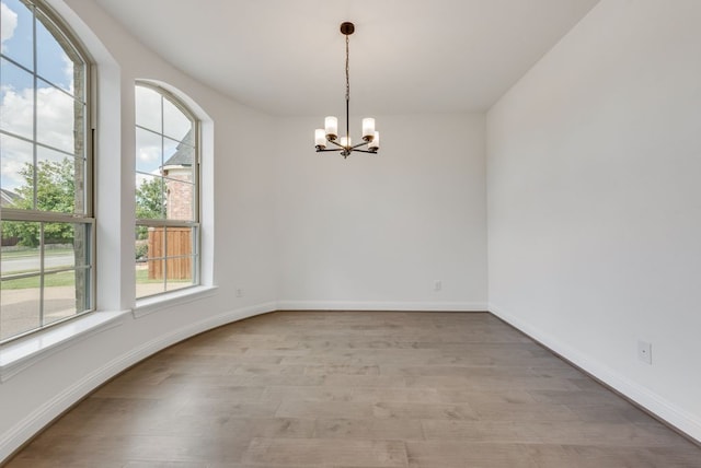 unfurnished room featuring a chandelier and light hardwood / wood-style flooring